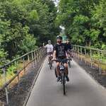 trójka rowerzystów na tle trasy rowerowej
